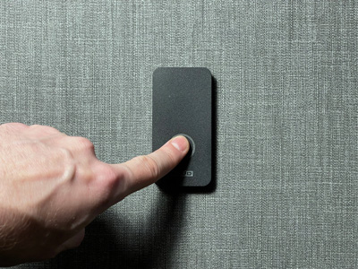 Черный считыватель для Болид СКУД, AXI3 на бетонной стене и демонстрацией нажатия кнопки для постановки на охрану